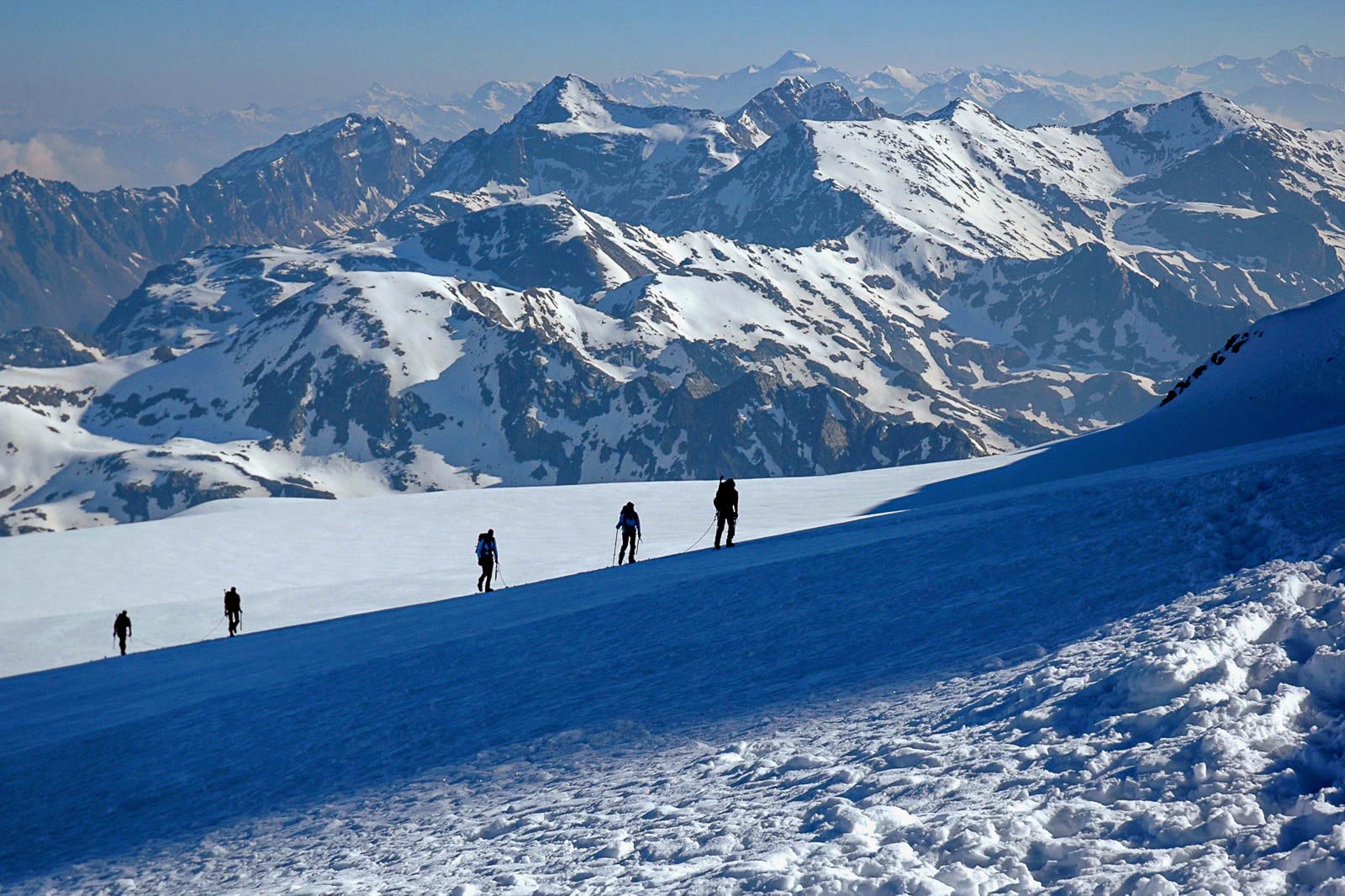 Cordate di alpinisti risalgono, di primo mattino, le affilate creste del monte Castore, 4228 m.